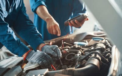 Close-up image of professional mechanics testing car battery with multimeter